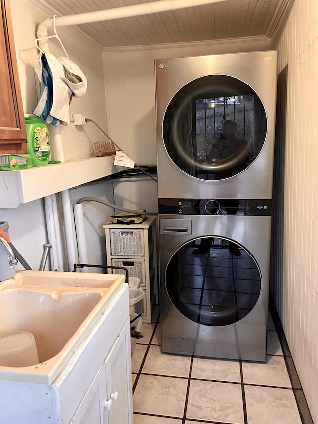 laundry room featuring laundry area, light tile patterned floors, wood ceiling, stacked washer / drying machine, and a sink