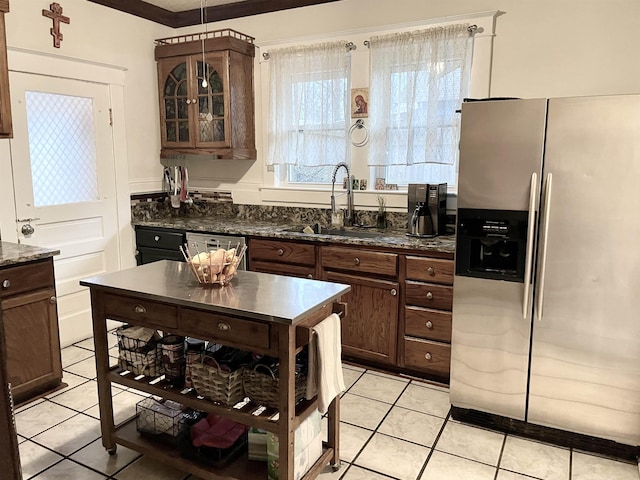 kitchen featuring stainless steel fridge, paneled dishwasher, glass insert cabinets, a sink, and light tile patterned flooring