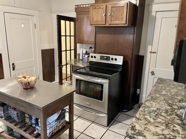 kitchen with light tile patterned floors, brown cabinetry, and stainless steel electric stove