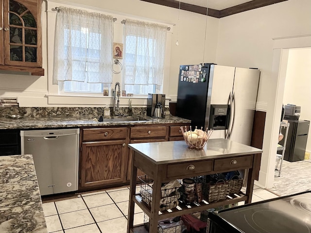 kitchen with dark stone counters, stainless steel appliances, a sink, and glass insert cabinets