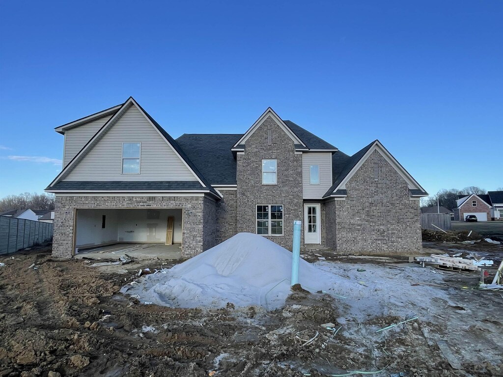 view of front facade featuring brick siding, an attached garage, and fence