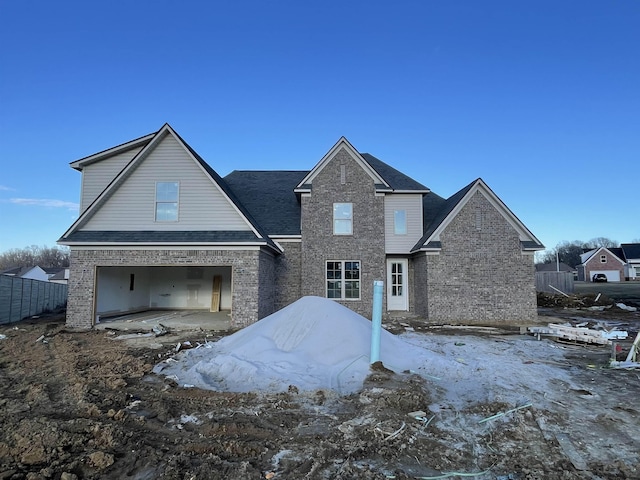 view of front facade featuring brick siding, an attached garage, and fence