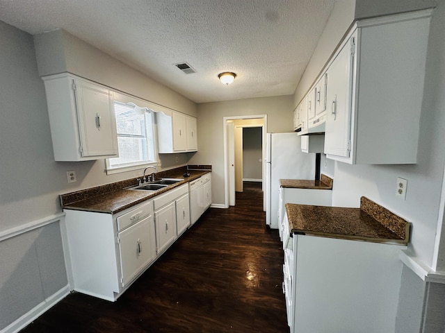 kitchen with dark wood-style floors, dark countertops, a sink, and visible vents