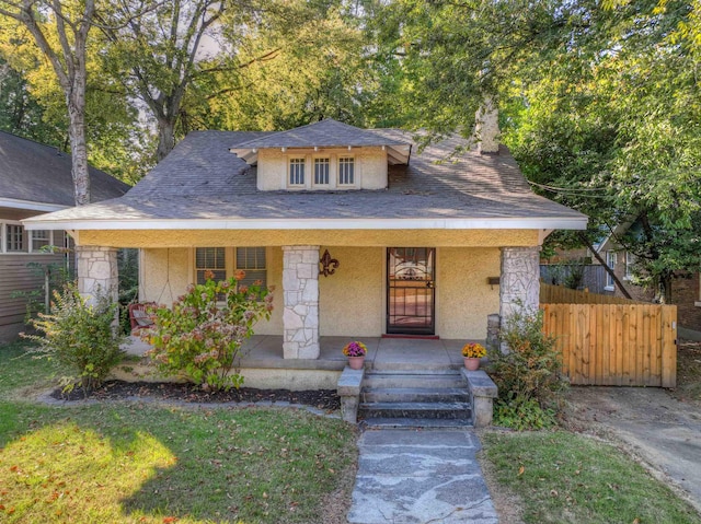 view of front of home with a porch, fence, and stucco siding