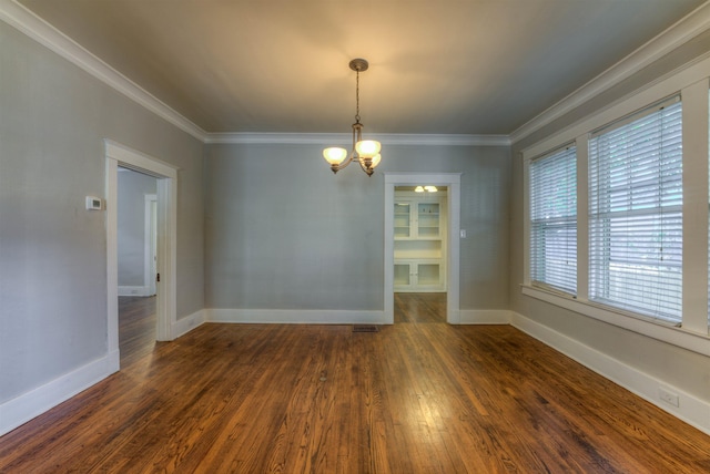 empty room featuring a notable chandelier, baseboards, wood finished floors, and crown molding