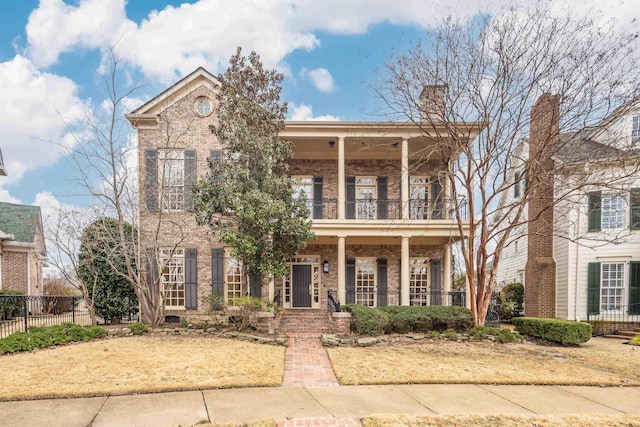 view of front facade featuring brick siding, fence, and a balcony