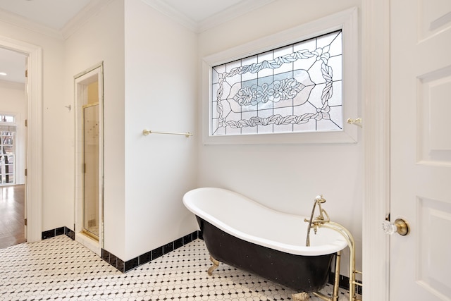 full bathroom featuring baseboards, ornamental molding, a soaking tub, tile patterned floors, and a stall shower