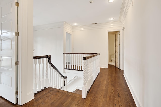 corridor with ornamental molding, visible vents, an upstairs landing, and wood finished floors