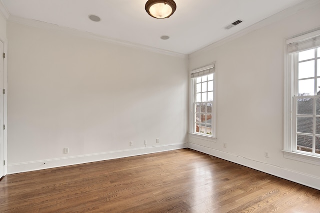 unfurnished room with baseboards, crown molding, visible vents, and wood finished floors