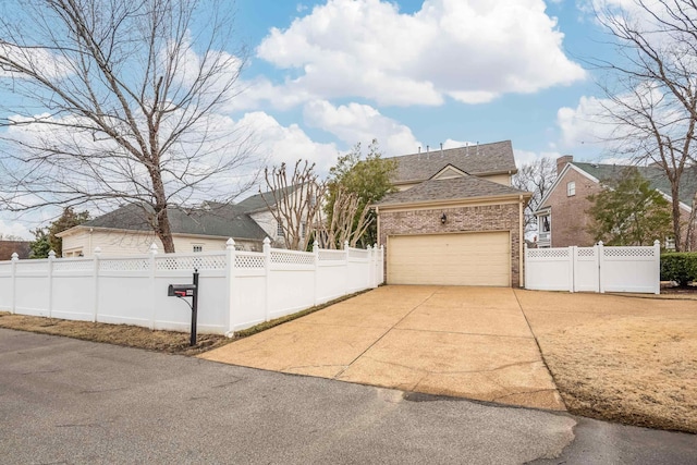 exterior space featuring a garage, driveway, brick siding, and a fenced front yard