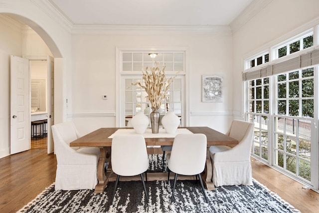 dining area with wood finished floors, a wealth of natural light, and crown molding