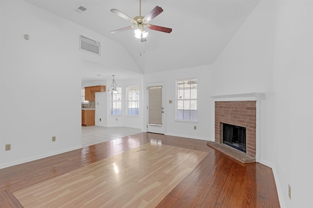 unfurnished living room featuring a brick fireplace, visible vents, and light wood-style floors