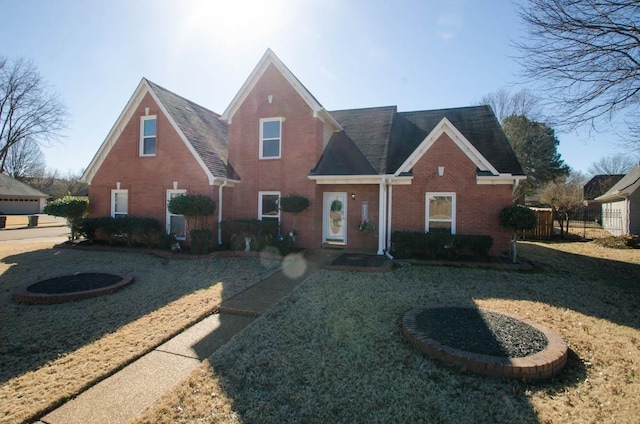 view of front of home featuring brick siding, fence, and a front lawn