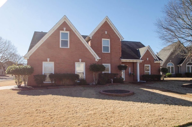 rear view of property featuring brick siding and a lawn