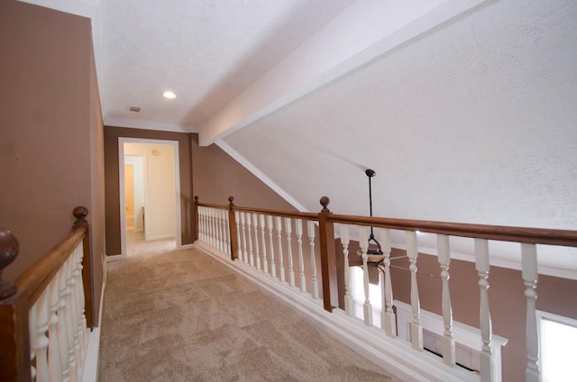 hall featuring vaulted ceiling with beams, visible vents, light carpet, a textured ceiling, and baseboards