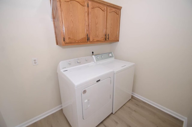 clothes washing area with light wood-type flooring, cabinet space, baseboards, and separate washer and dryer