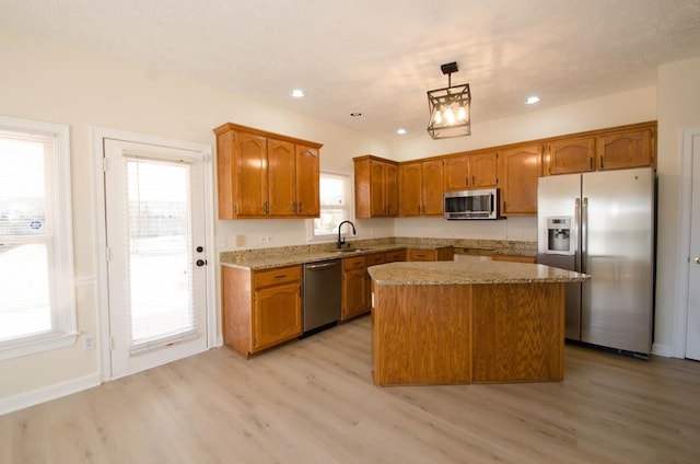 kitchen with stainless steel appliances, brown cabinetry, light wood-type flooring, and a kitchen island