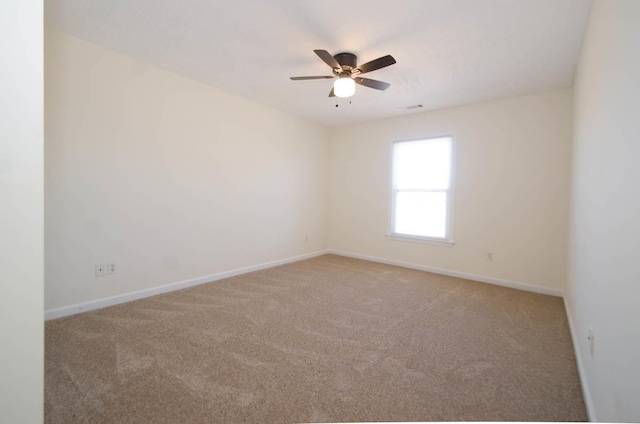 empty room with ceiling fan, carpet flooring, visible vents, and baseboards