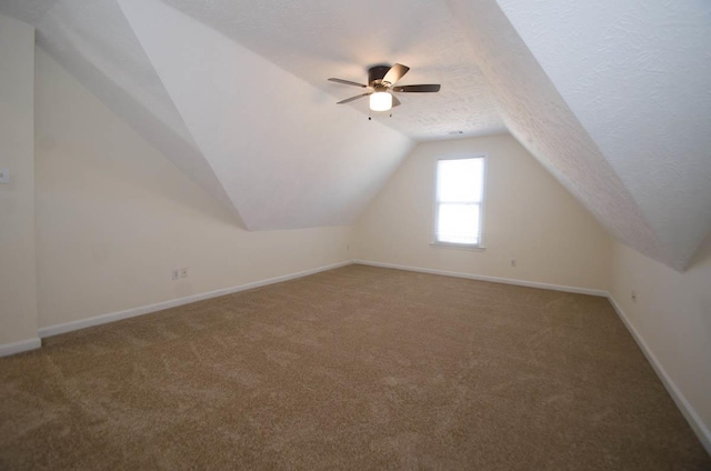 bonus room with baseboards, ceiling fan, vaulted ceiling, a textured ceiling, and carpet floors