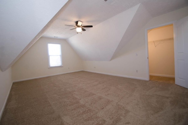 bonus room with a textured ceiling, carpet floors, a ceiling fan, baseboards, and vaulted ceiling