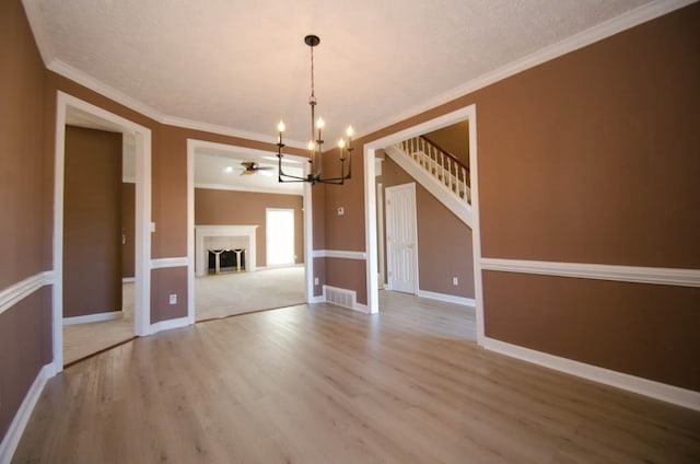 spare room with a fireplace, wood finished floors, visible vents, baseboards, and stairs