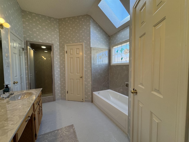 full bathroom featuring vaulted ceiling with skylight, wallpapered walls, a shower stall, and vanity