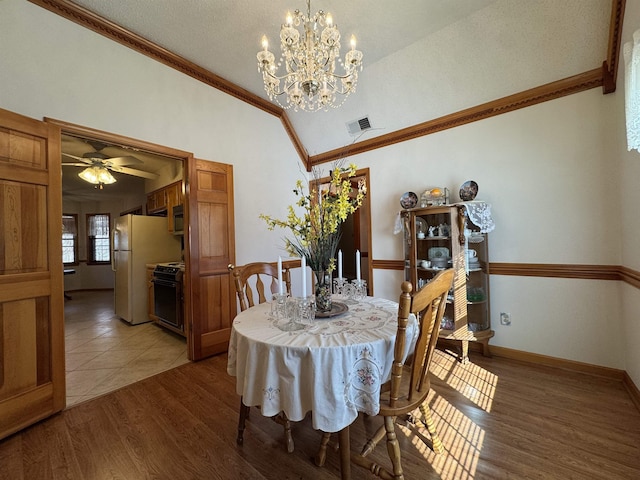 dining space featuring light wood-type flooring, visible vents, vaulted ceiling, and ornamental molding