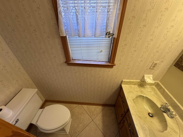 bathroom with toilet, vanity, baseboards, tile patterned floors, and wallpapered walls