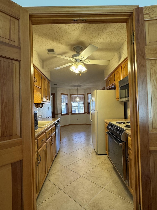 kitchen with stainless steel appliances, brown cabinetry, light countertops, and wallpapered walls