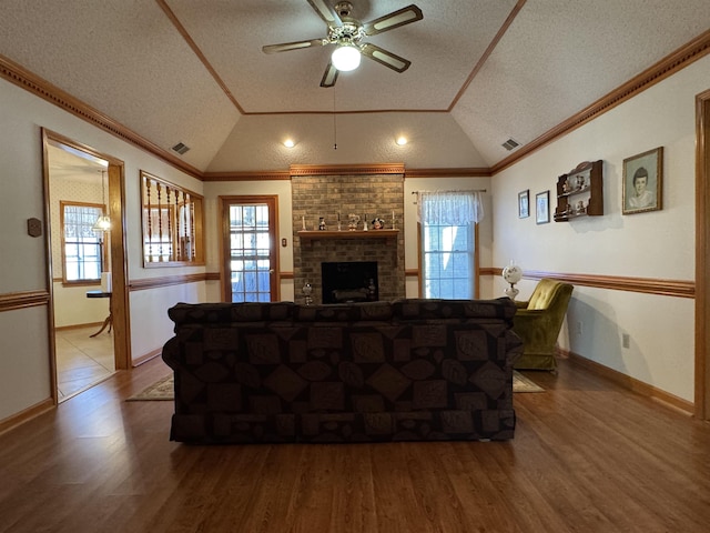 living area with lofted ceiling, a healthy amount of sunlight, visible vents, and crown molding