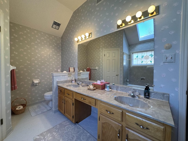 full bathroom with vaulted ceiling with skylight, toilet, a sink, visible vents, and wallpapered walls