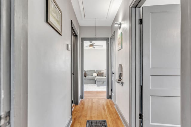 hallway featuring attic access, visible vents, and light wood-style flooring