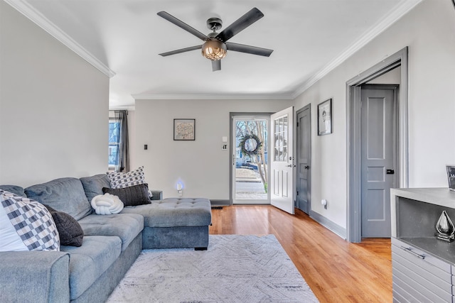 living room featuring baseboards, light wood-style flooring, a wealth of natural light, and crown molding