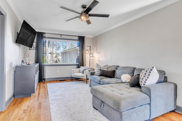 living room featuring light wood finished floors, ceiling fan, and ornamental molding