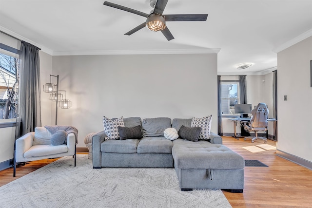 living area featuring light wood-style flooring, baseboards, and crown molding