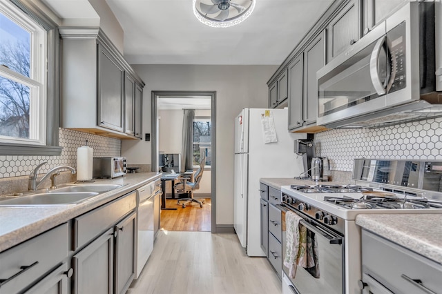 kitchen with white appliances, a sink, and gray cabinetry