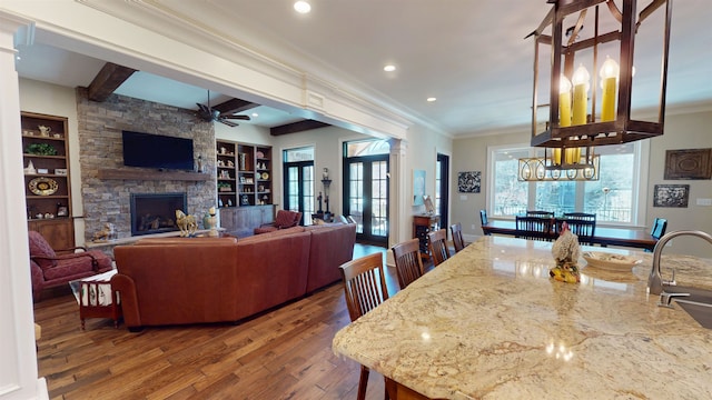 interior space featuring a fireplace, a ceiling fan, hardwood / wood-style floors, decorative columns, and crown molding