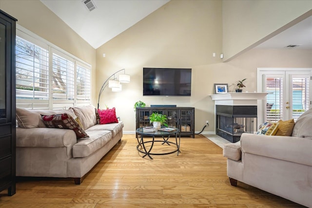 living room featuring a healthy amount of sunlight, visible vents, and light wood-style floors