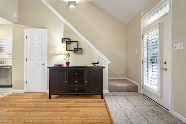 foyer featuring lofted ceiling, baseboards, and light tile patterned floors