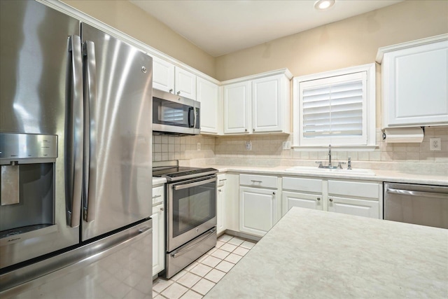 kitchen featuring light tile patterned floors, stainless steel appliances, tasteful backsplash, light countertops, and a sink