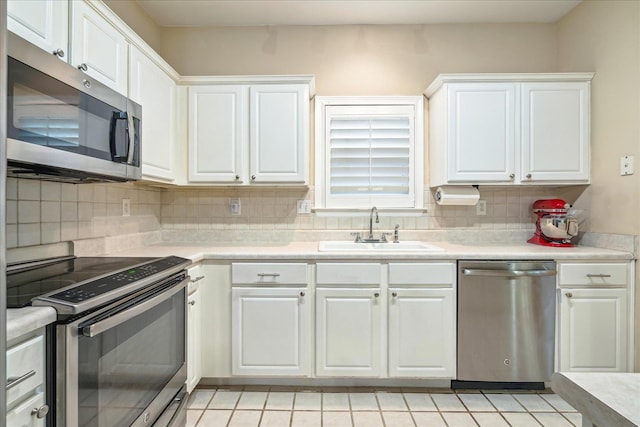 kitchen featuring tasteful backsplash, appliances with stainless steel finishes, light countertops, white cabinetry, and a sink