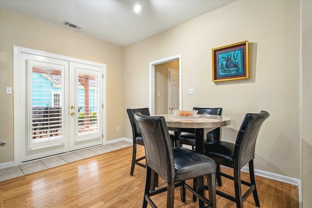 dining space with light wood-type flooring, baseboards, visible vents, and french doors