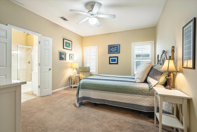 bedroom featuring ceiling fan, light colored carpet, visible vents, baseboards, and ensuite bath