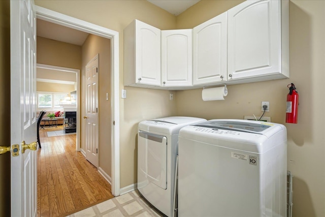 laundry area with light wood-type flooring, cabinet space, baseboards, and washing machine and clothes dryer