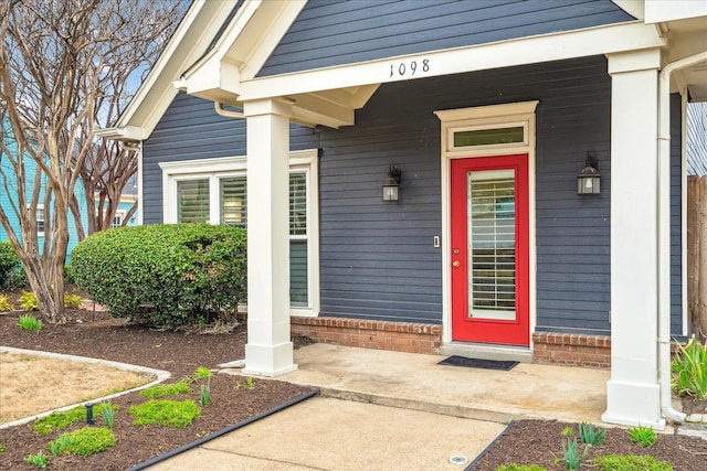 entrance to property with a porch and brick siding