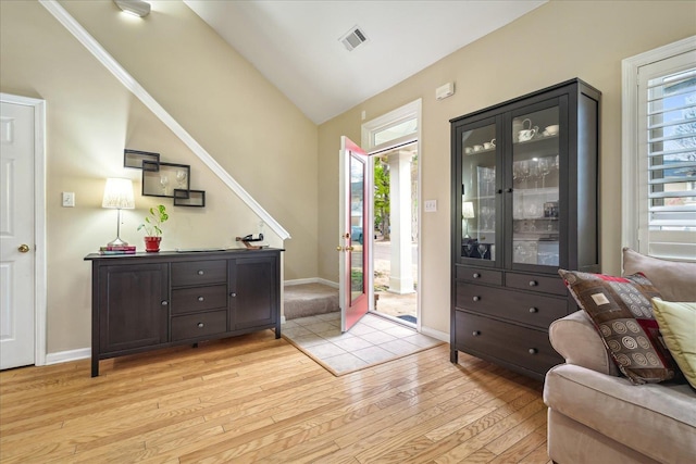 entryway featuring lofted ceiling, baseboards, visible vents, and light wood finished floors