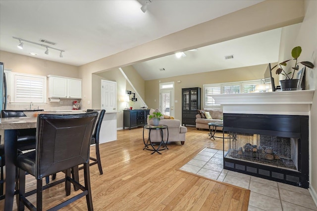 dining space featuring light wood finished floors, a fireplace with flush hearth, and visible vents