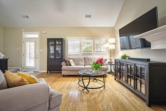 living room with lofted ceiling, plenty of natural light, visible vents, and wood finished floors