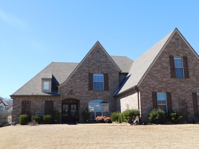 view of front of property featuring a shingled roof, french doors, and brick siding