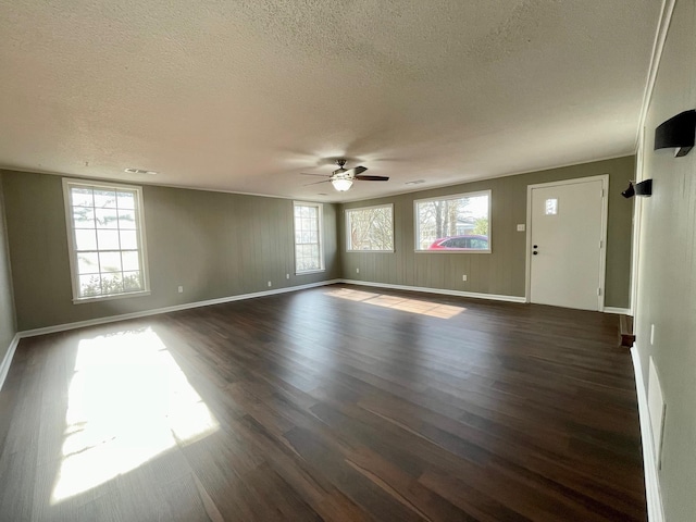 empty room featuring a textured ceiling, dark wood-style flooring, visible vents, and a ceiling fan